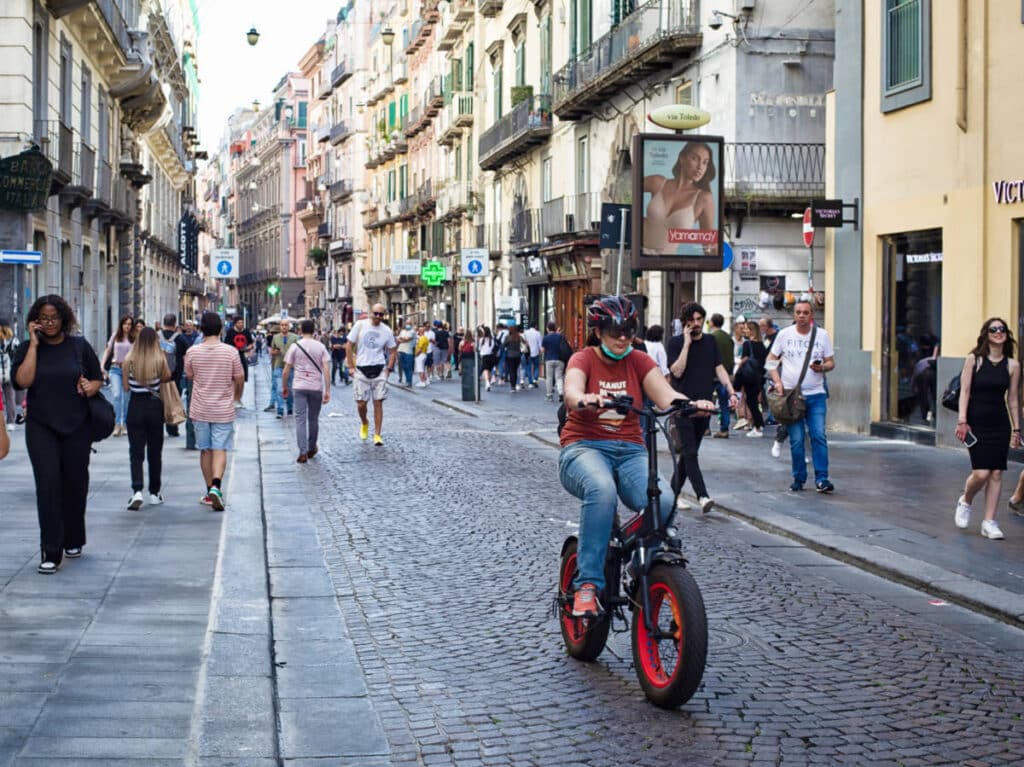 A woman biking in the middle of the busy street in Naples