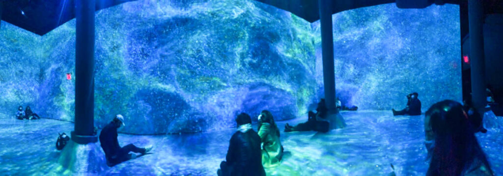 People admiring the 360-degree view of rotating art installations in ARTECHOUSE NYC