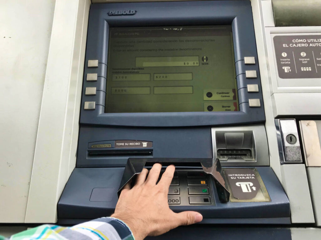 A hand on the keypad of the ATM