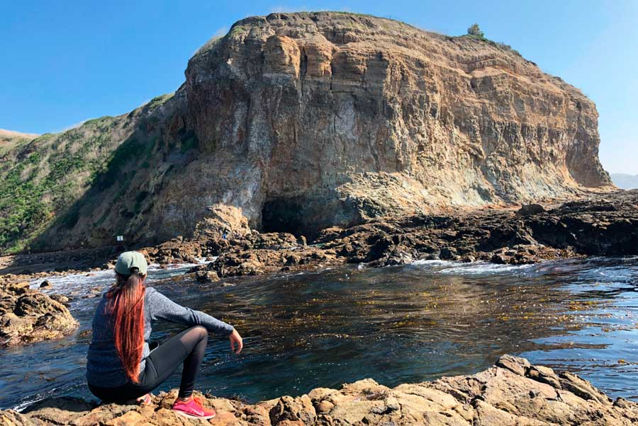 A woman sitting on a rock on the shoreline of Abalone Cove