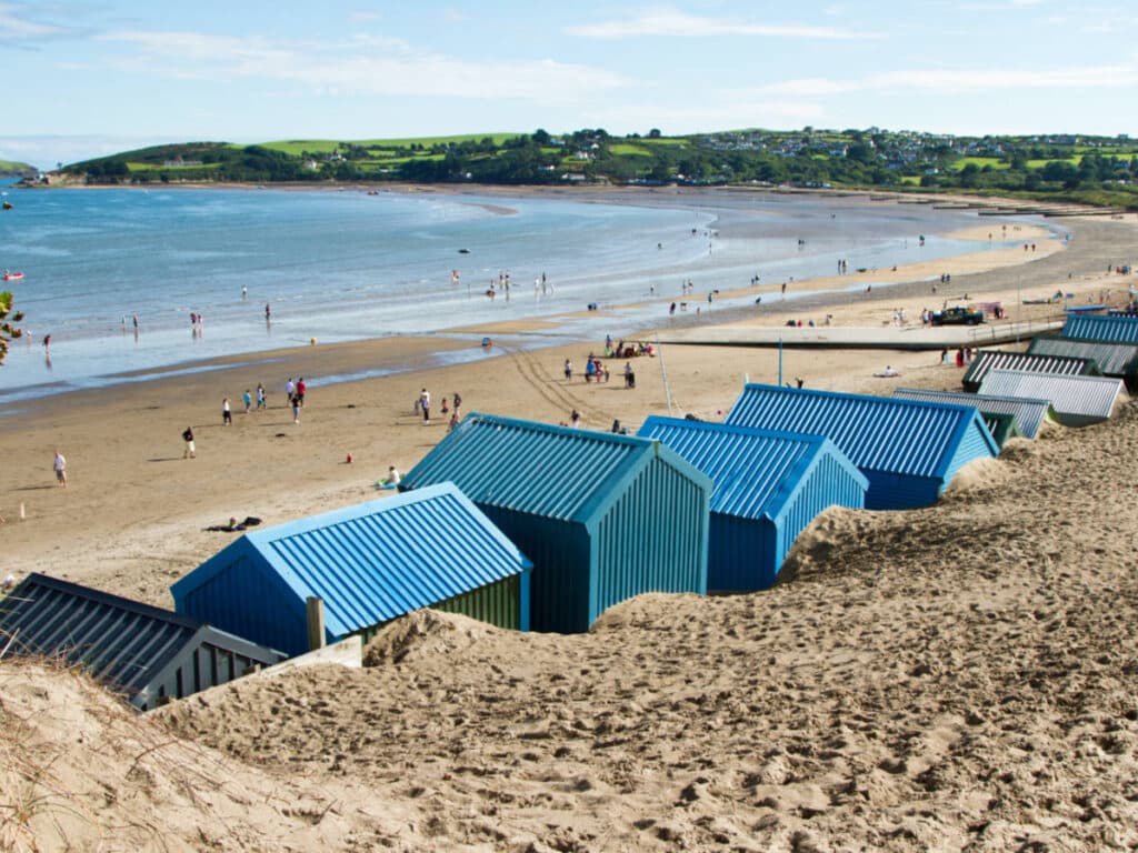 View of the blue beach huts and the people at the white sand Abersoch beach