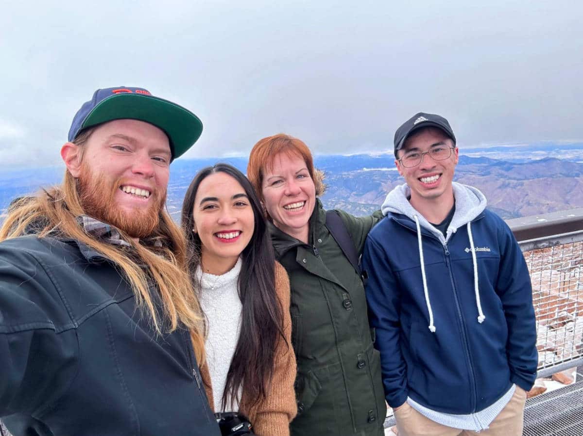 The author Abigail Bliss and her family, posing for a photo with the summit views at Pikes Peak Cog Railway