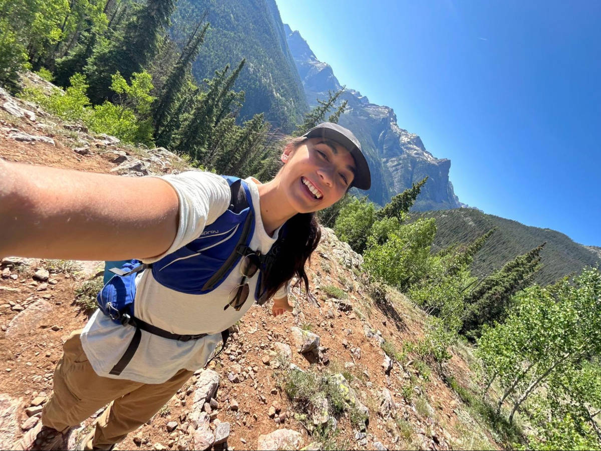 The author Abigail Bliss smiling for a photo with a scenic view in summertime