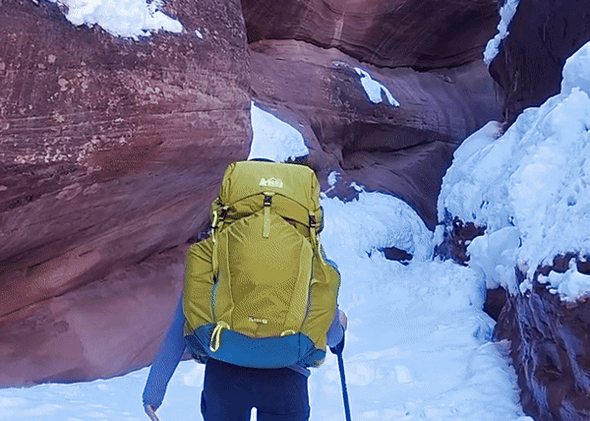 The author, Abigail, hiking while carrying the REI Co-Op Flash 55 Backpack and using a trekking pole