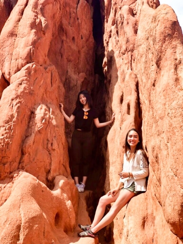 Travel Lemming editor Abigail with her friend posing in between the red rock formation at the Garden of the Gods