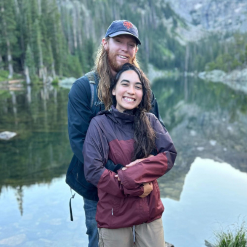The author Abigail Bliss and her husband hugging near the scenic lake