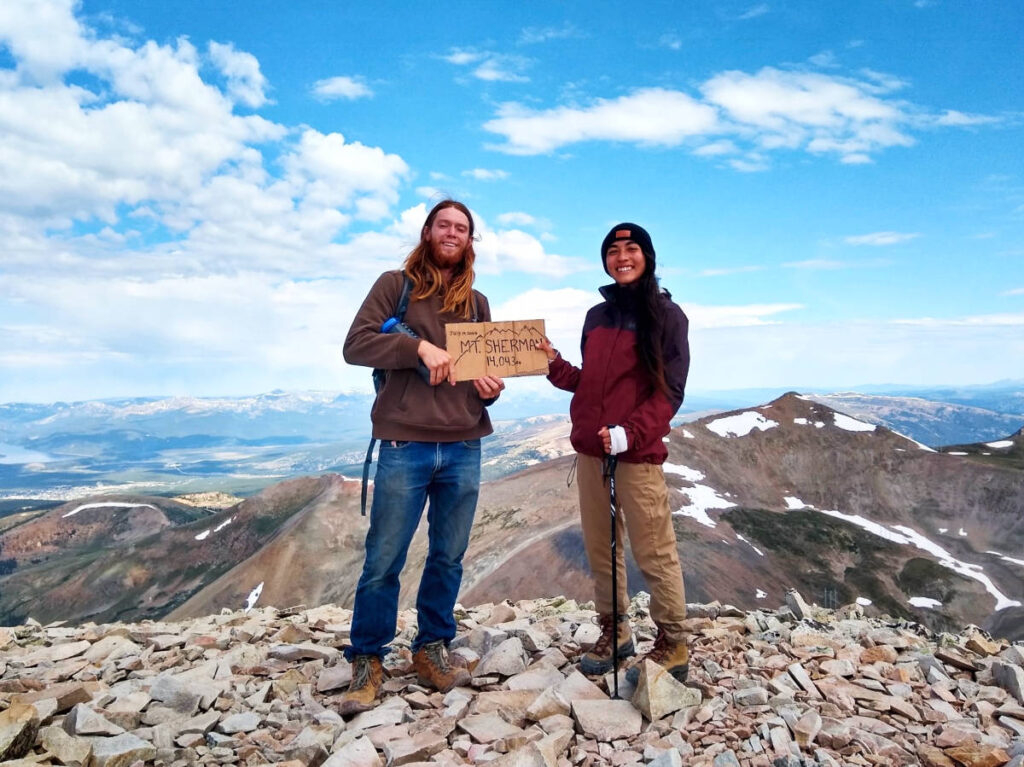 The author Abigail and her husband holding a signage on the Mt Sherman summit