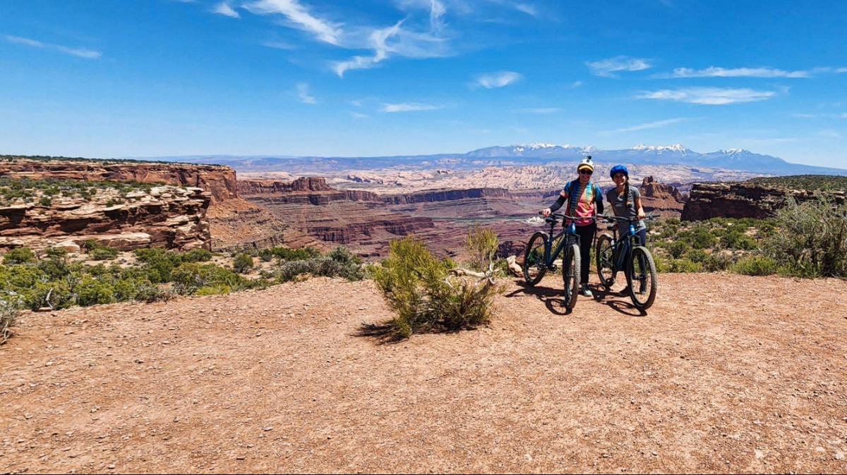 Travel Lemming Editor Abigail and her friend, Skycie, posing with their bikes with an overlooking view at the Great Pyramid trail