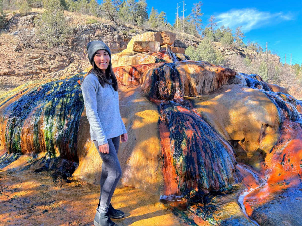 The author Abigail Bliss posing for a photo at the colorful rocks at Pinkerton Hot Springs