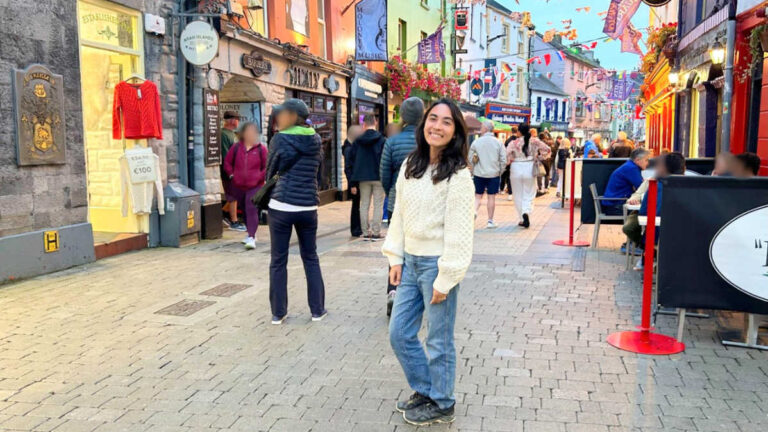 The author Abigail Bliss posing for a photo in the middle of The Latin Quarter with colorful buildings around