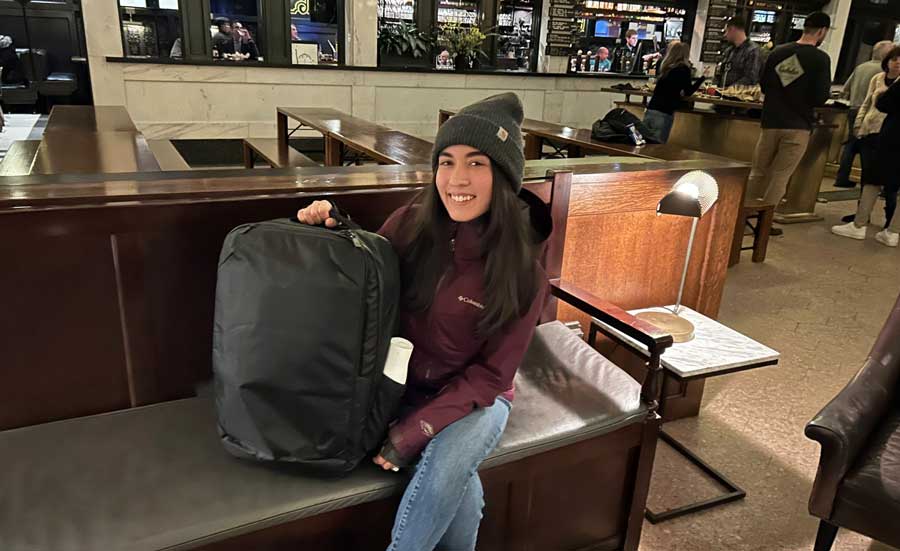 The author sitting inside Denver Union Station holding her Tortuga Travel Backpack