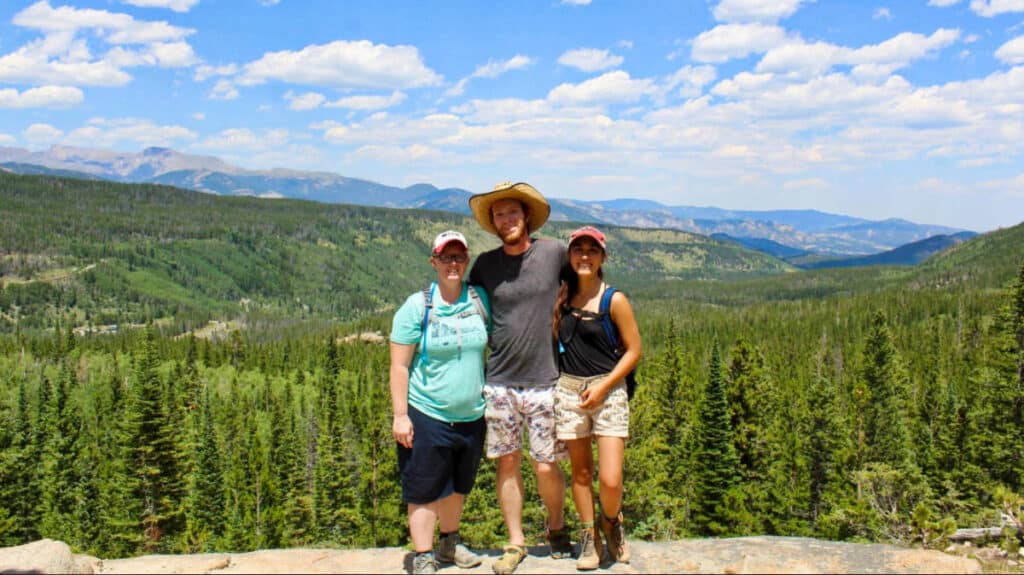 Travel Lemming editor Abigail Bliss, with her family posing at the Four Lake Loop Trail with a scenic view in the background