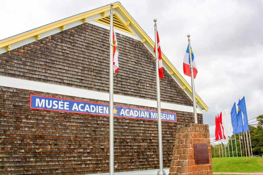 The outer facade of the Acadian Museum with different flags in Miscouche PEI