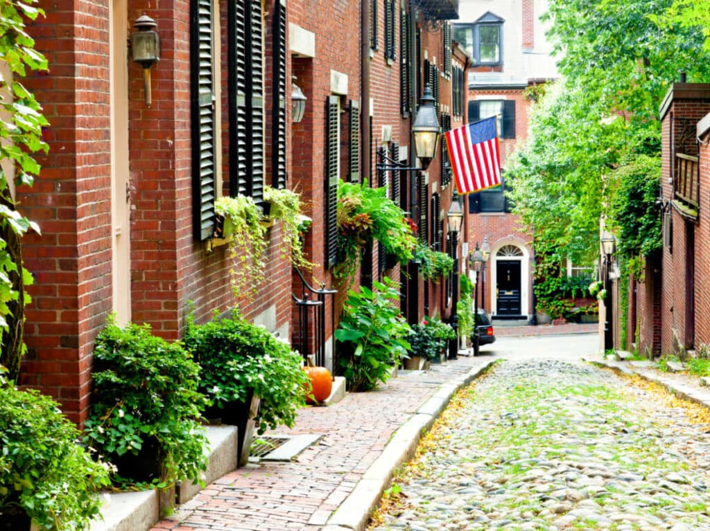 A US flag on one of the buildings with cobblestone streets in the Acorn Street