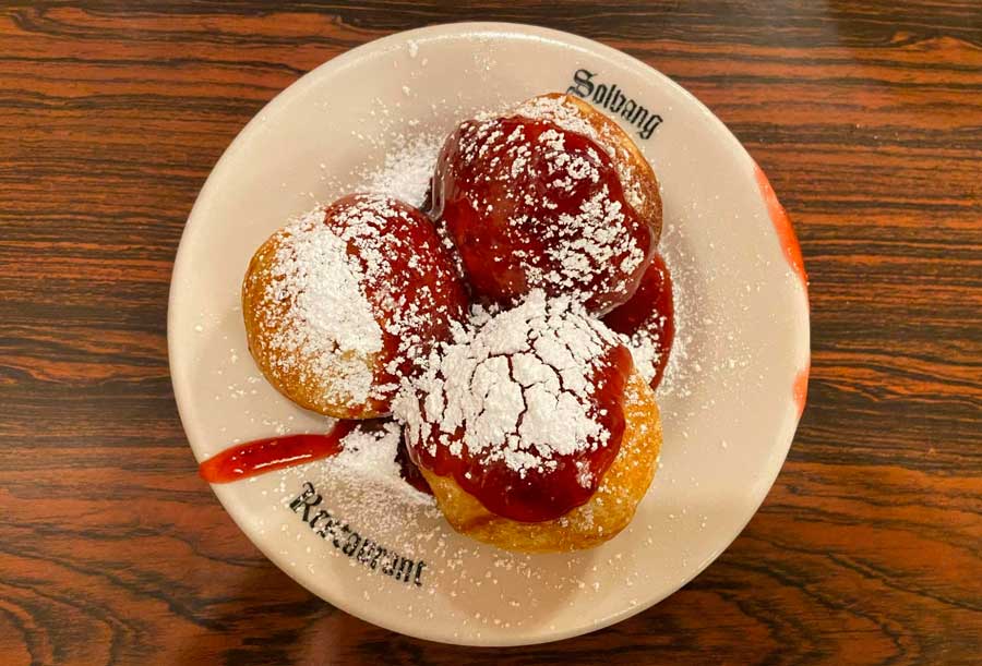 A pastry topped with powdered sugar and strawberry syrup on a plate