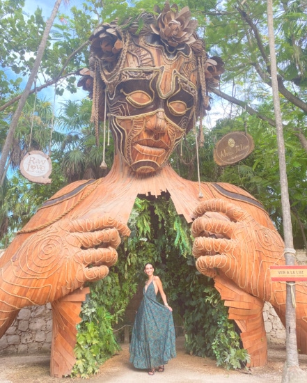 Woman standing in front of the statue at Ahau Tulum