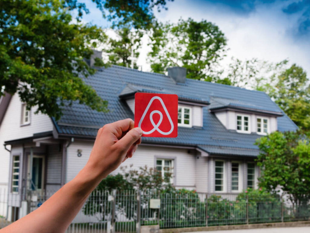 A hand holding an AirBnb logo