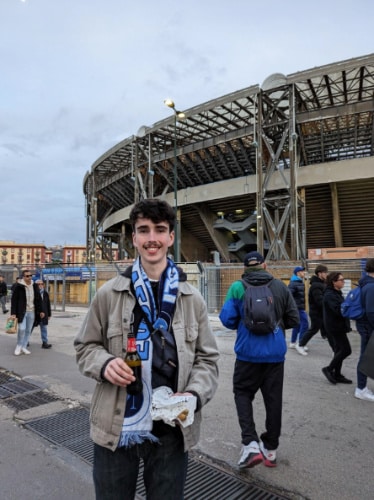 Alex Brotherton smiling for a photo outside a stadium in Naples, Italy