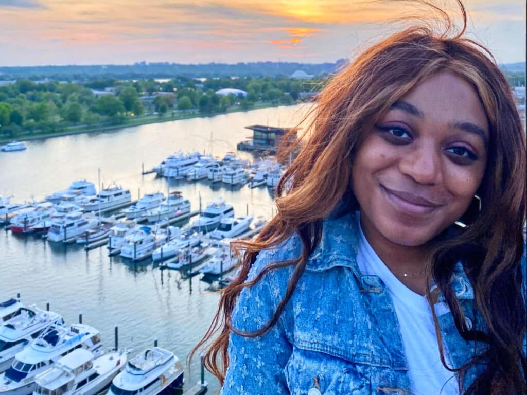 The author Alexandria Taylor, posing with the docked boats and beautiful sunset in the background