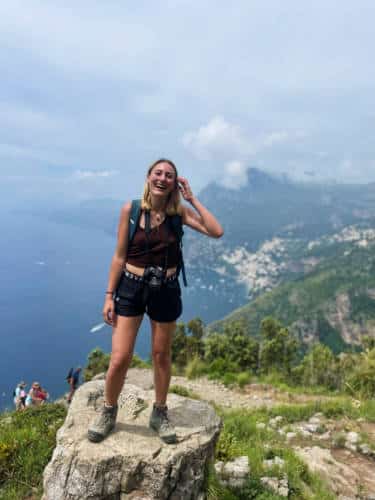 The author, Sky Ariella smiling for a photo on top of a rock in Amalfi Coast