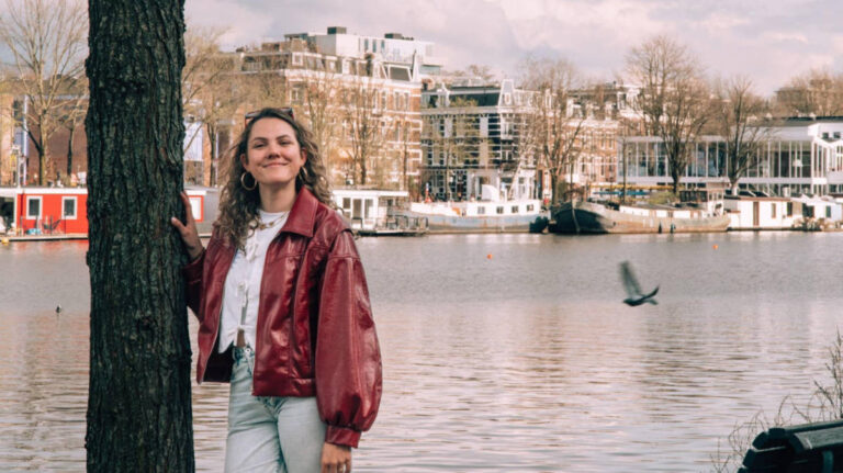 The author Amber Visch posing for a photo with the river Amstel in the background