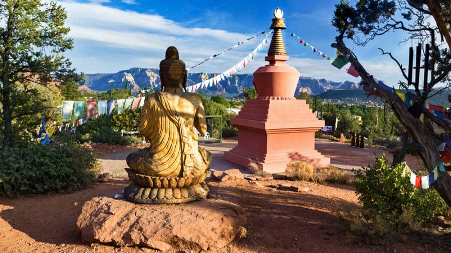 A Buddha Statue near a small tower with buntings around in Sedona