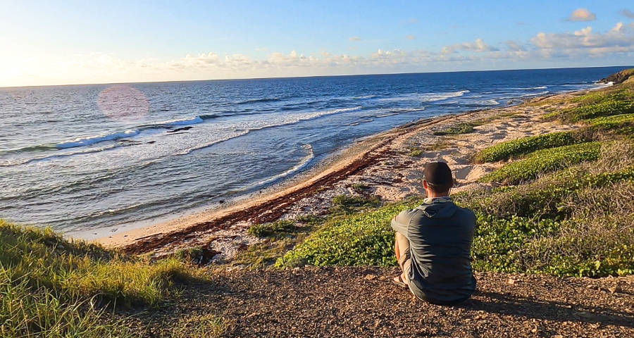 A man sitting on the ground while watching the beautiful sunrise on the beach at St. Croix