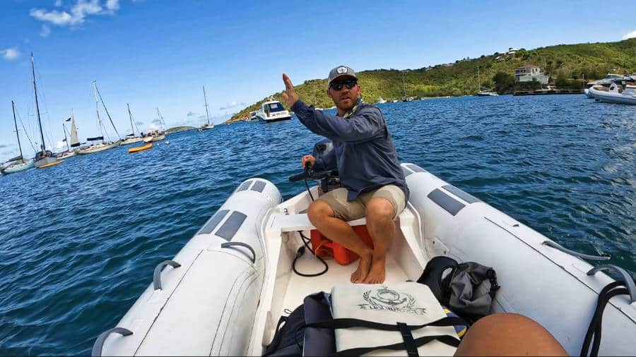 The author Andrew Bloem riding a boat with sailing boats and mountain ranges in the background