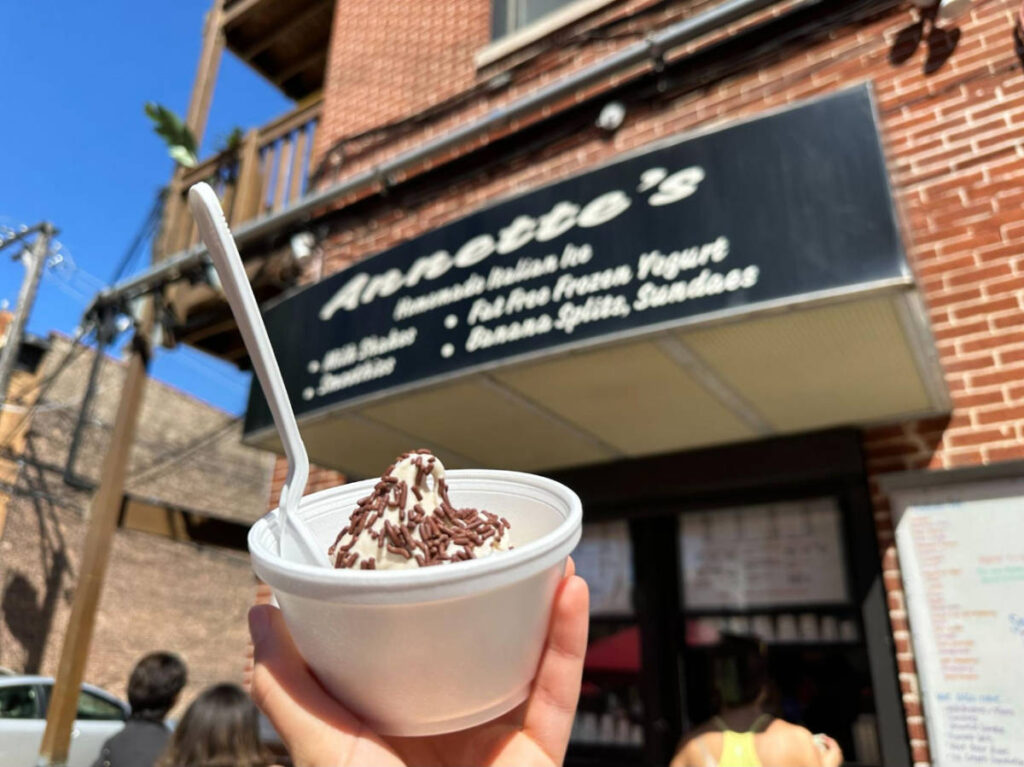 A hand holding a frozen yogurt from Annette's Italian Ice