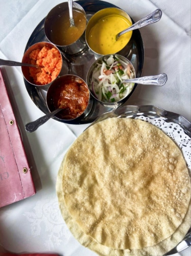 A plate of appam with different sauces on the side