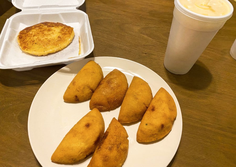 A plate of beef empanadas, arepas, and mango milkshake from Aracely's Sazón Colombian Restaurant