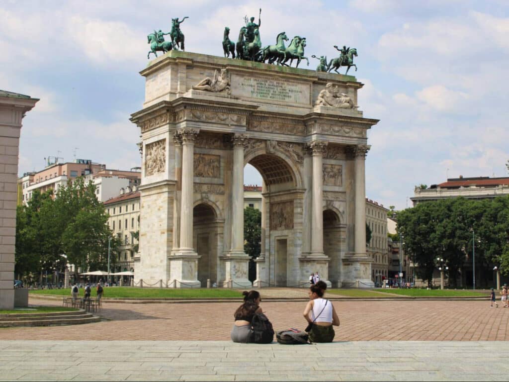 Two women sitting across the Arco Della Pace