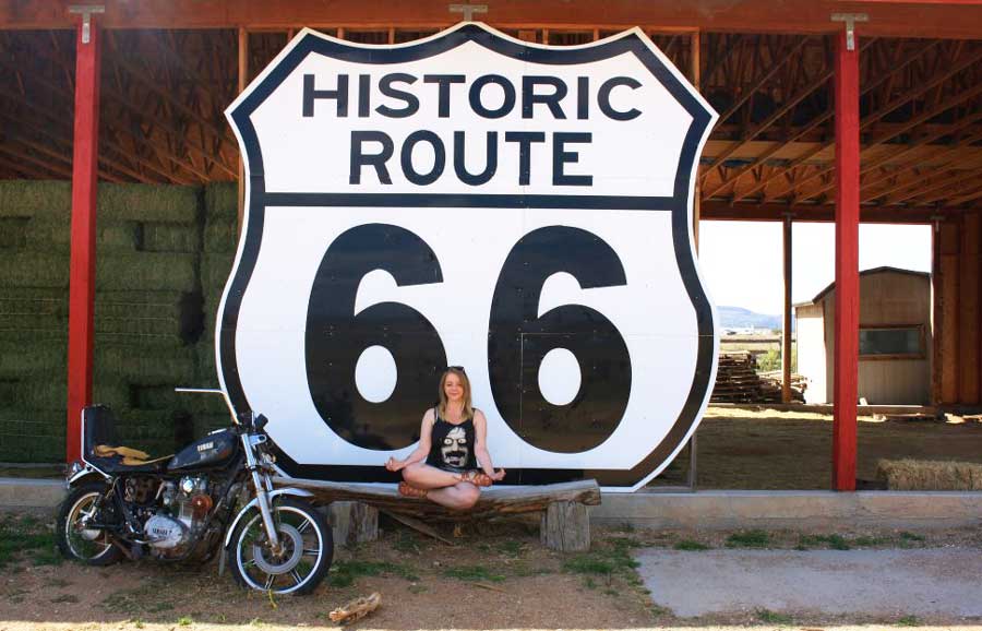 Travel Lemming editor Taylor posing for a photo on a big sign of Arizona Route 66