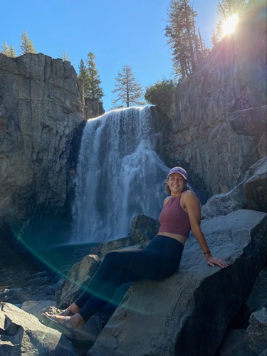 Ashleigh Bandimere smiling for a photo with the Rainbow Falls on her background