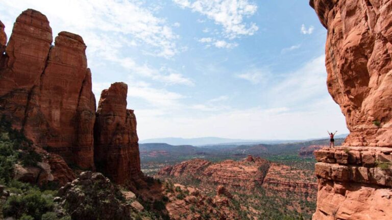 View from a distance of a woman posing near the cliff next to Cathedral Rock