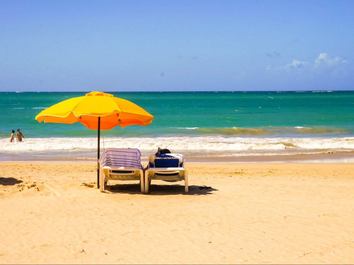 Beach chairs under a yellow umbrella at Isla Verde Beach