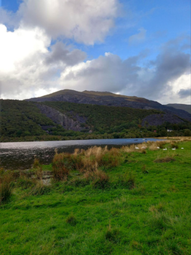 Field of grass near a lake with a mountain backdrop at Llanberis