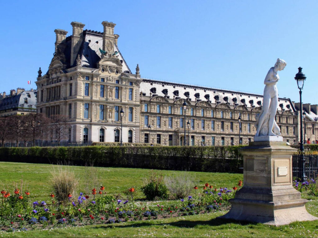 A Parisian palace featuring statues and flowers within Tuileries Gardens