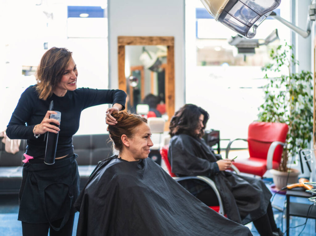 A hairdresser adjusts a client's hair in a salon
