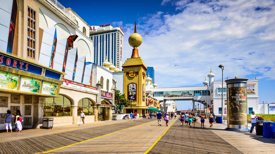 Tourists walking on the vibrant boardwalk of Atlantic City with shops around.