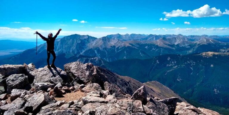 Author Abigail celebrates at the summit of a 14er with arms wide open