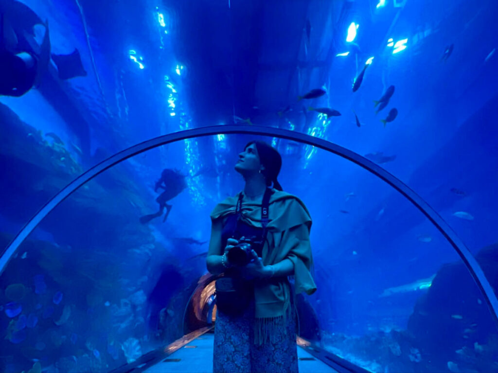 Author Betty looking up to see the fishes in Dubai Aquarium