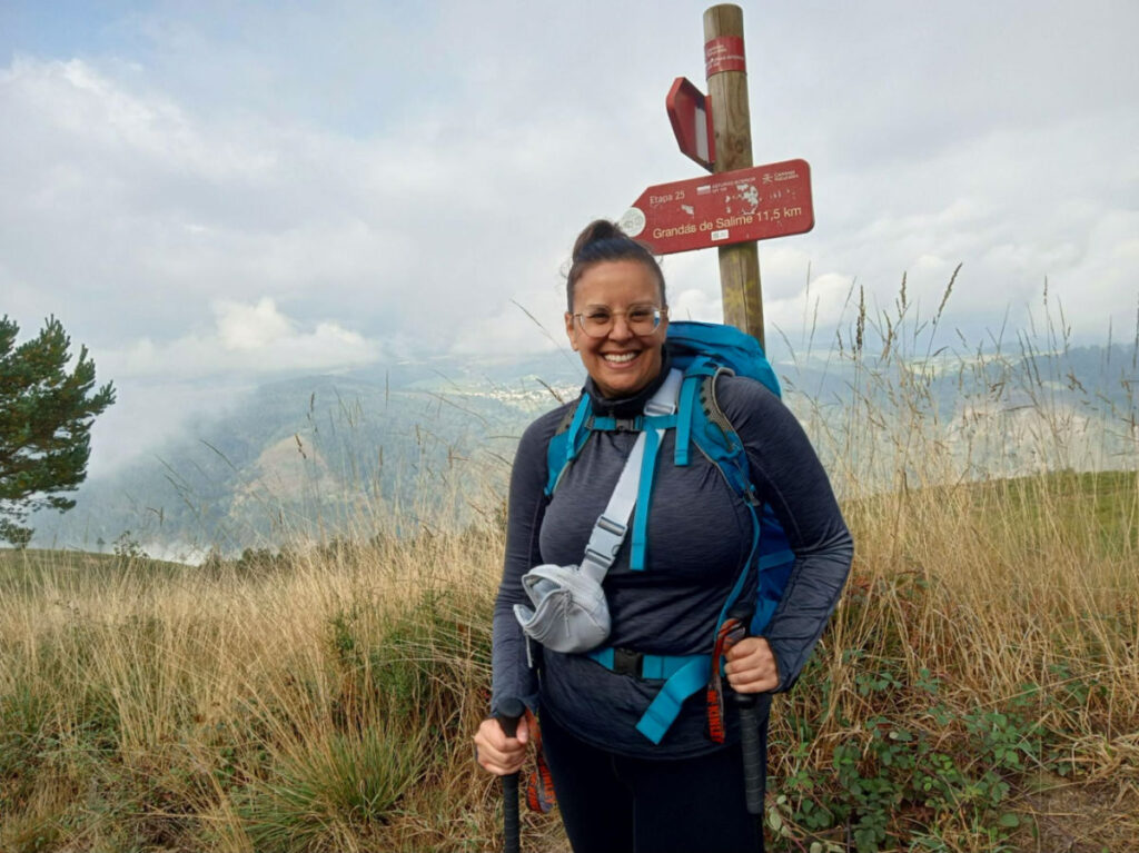 Author Catherine standing at the direction sign at Camino Primitivo on a foggy day