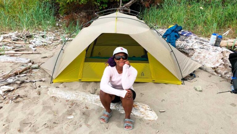 Author Chelsea sitting in a driftwood near her tent