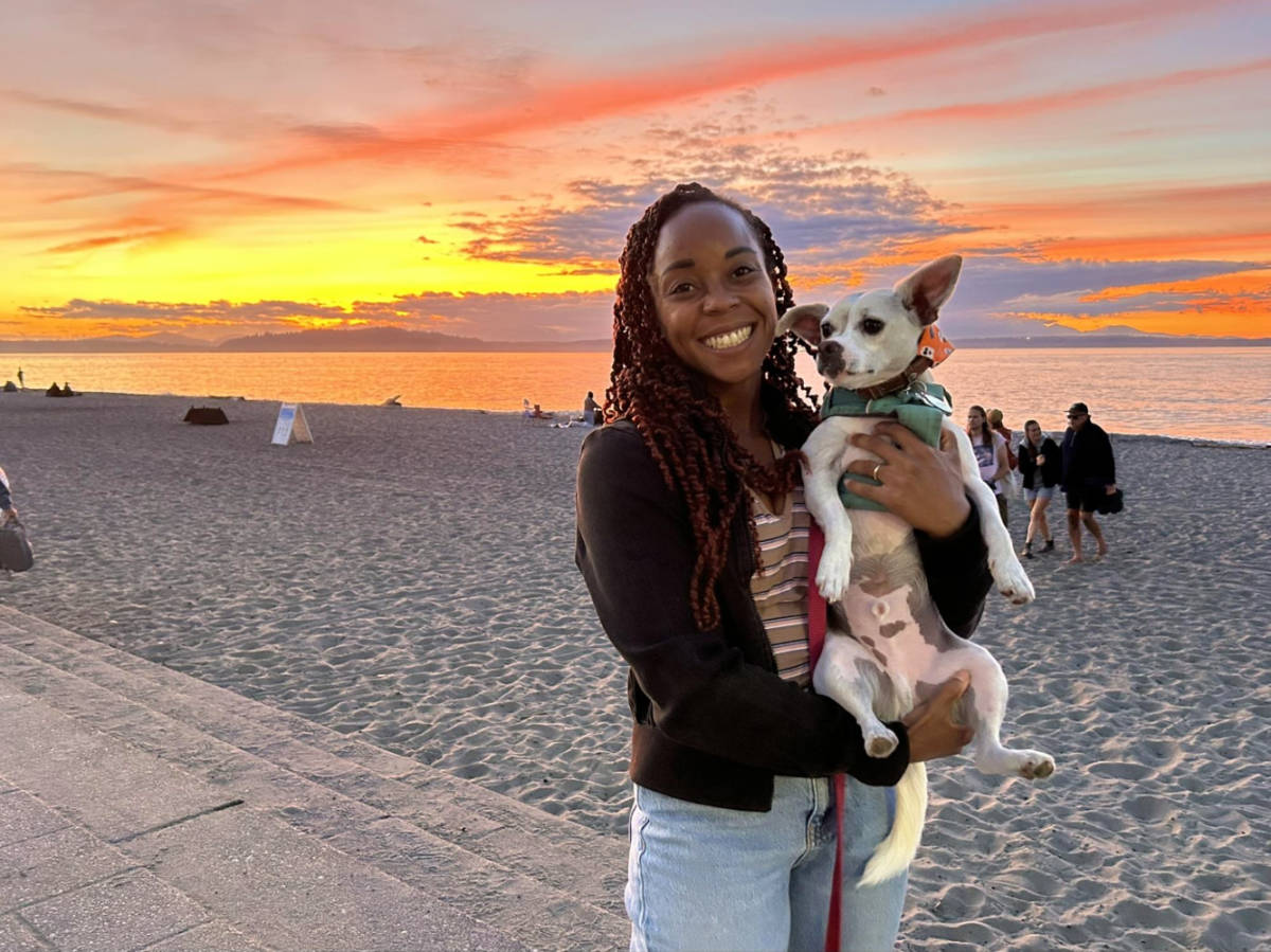 Author Chelsea holding her dog at Alki Beach during sunset