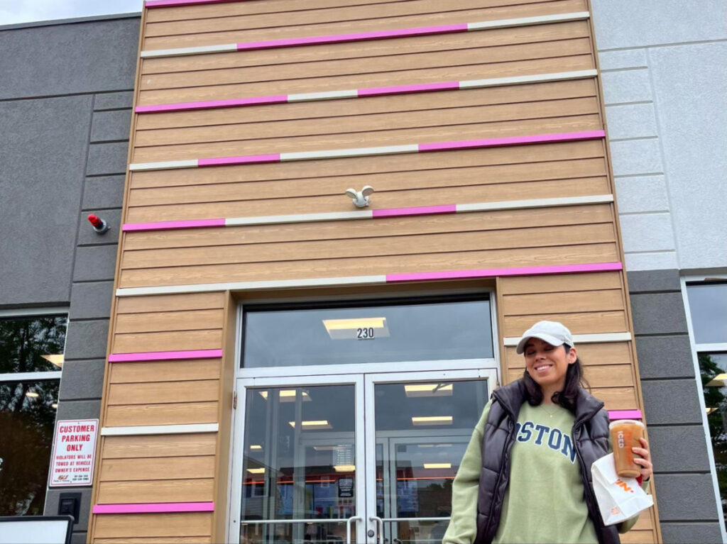 Author Claudicet holding an iced coffee in front of Dunkin