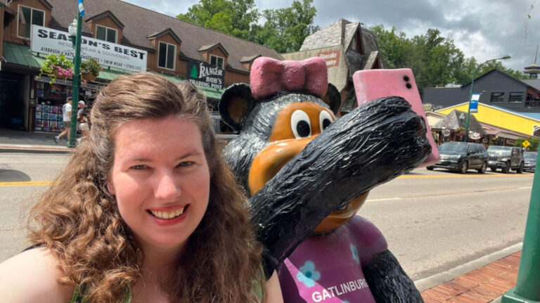 Author Elizabeth taking a selfie with a bear statue wearing a shirt that says Gatlinburg