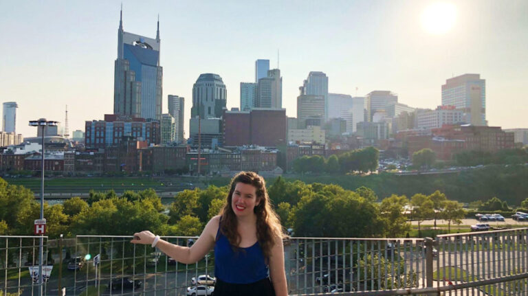 The author Elizabeth Demolat posing in front of the Nashville skyline on a sunny day