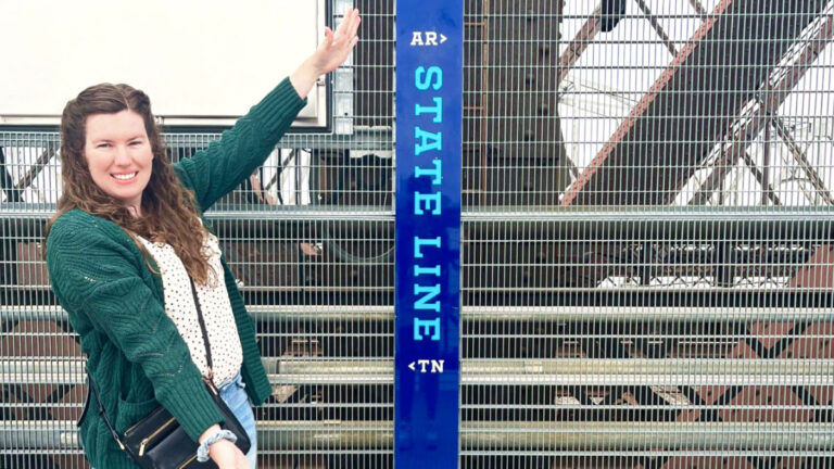 The author Elizabeth posing at the Tennessee-Arkansas state line