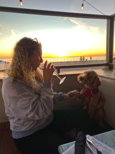 Author Jess drinking wine while holding her dog at Dini’s By The Sea